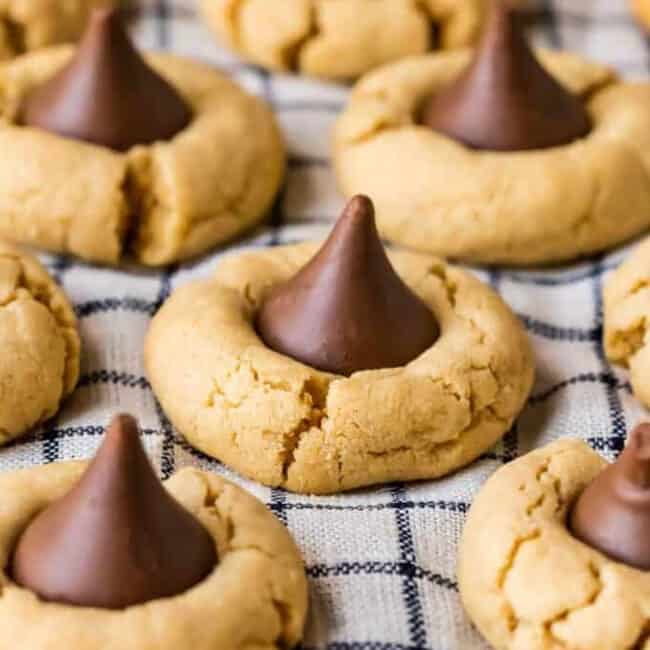 Peanut butter cookies with chocolate kisses, known as hershey kiss cookies or peanut butter kiss cookies, arranged on a baking sheet.