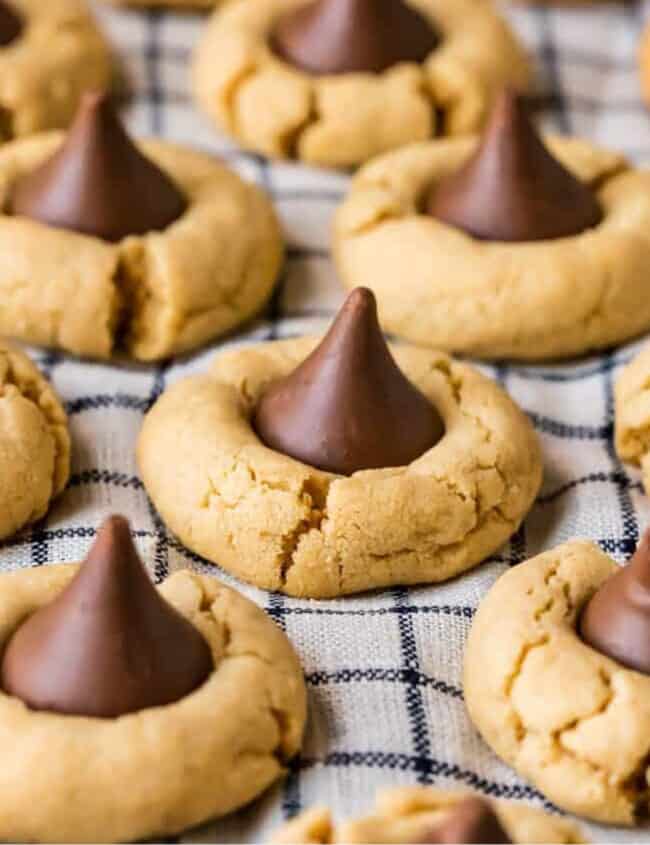 Peanut butter cookies with chocolate kisses, known as hershey kiss cookies or peanut butter kiss cookies, arranged on a baking sheet.