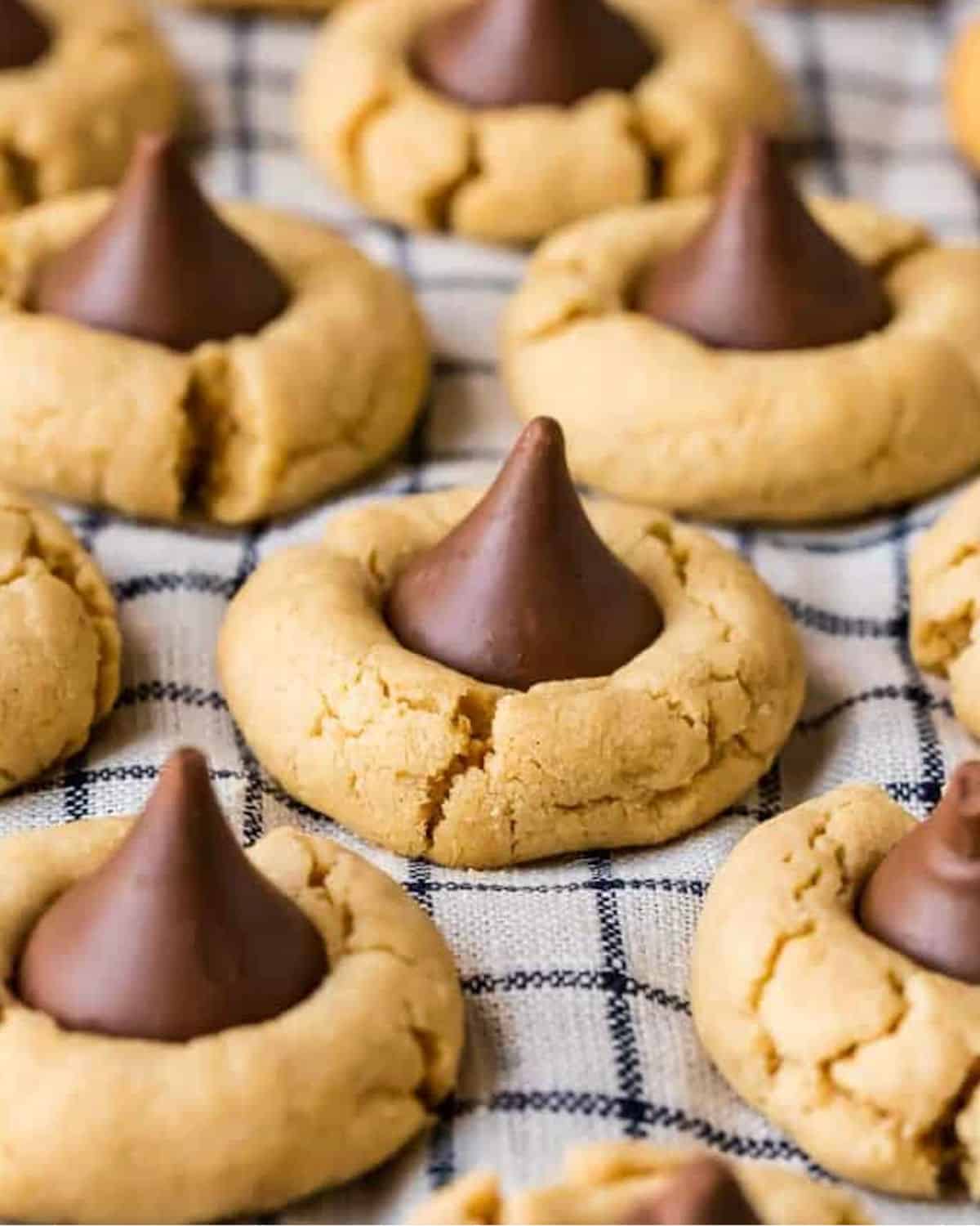 Peanut butter cookies with chocolate kisses, known as hershey kiss cookies or peanut butter kiss cookies, arranged on a baking sheet.