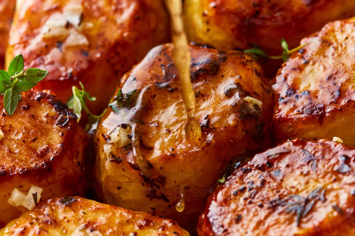 A close up of grilled potatoes being drizzled with honey.