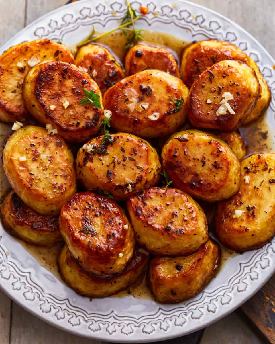 A plate of roasted potatoes on a wooden table.
