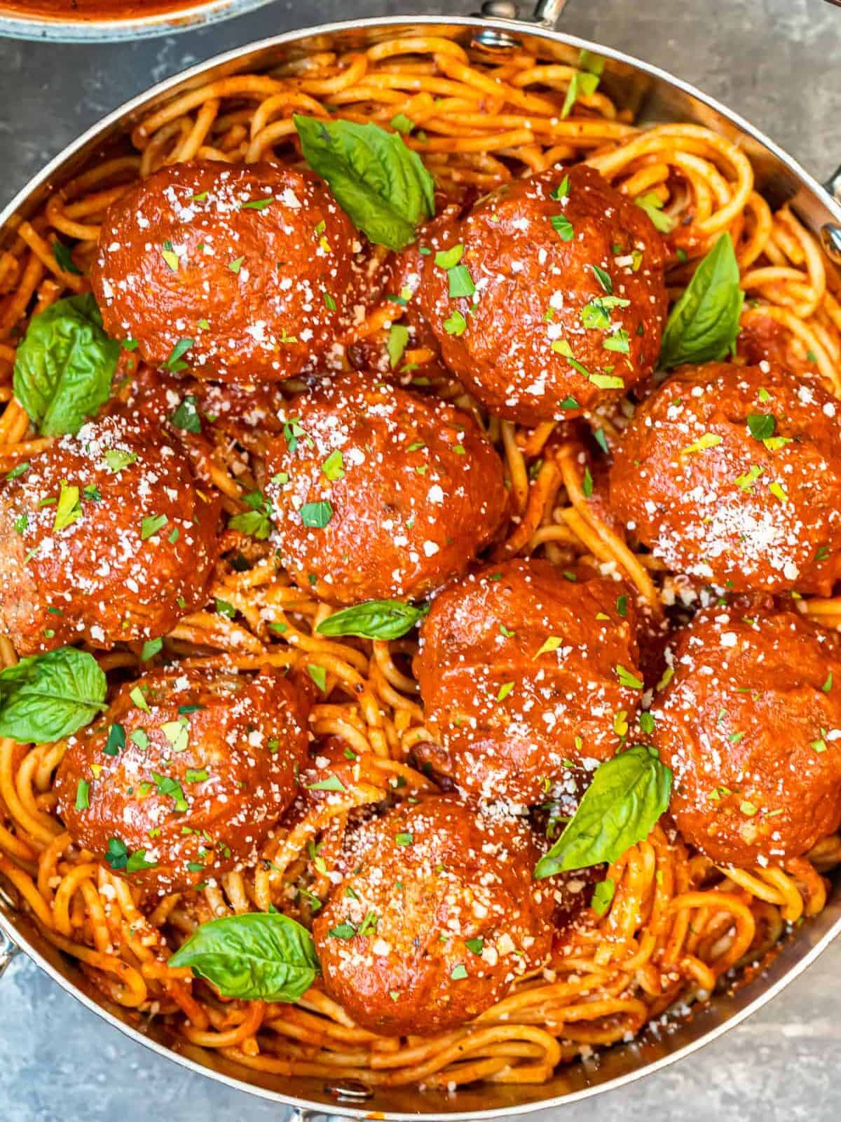 meatballs over pasta in a pan.