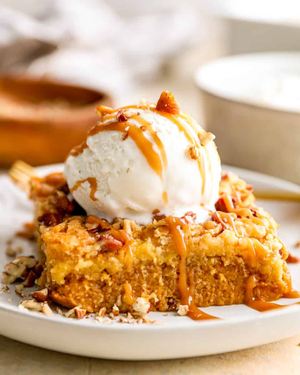 A piece of pumpkin dump cake topped with a scoop of ice cream.