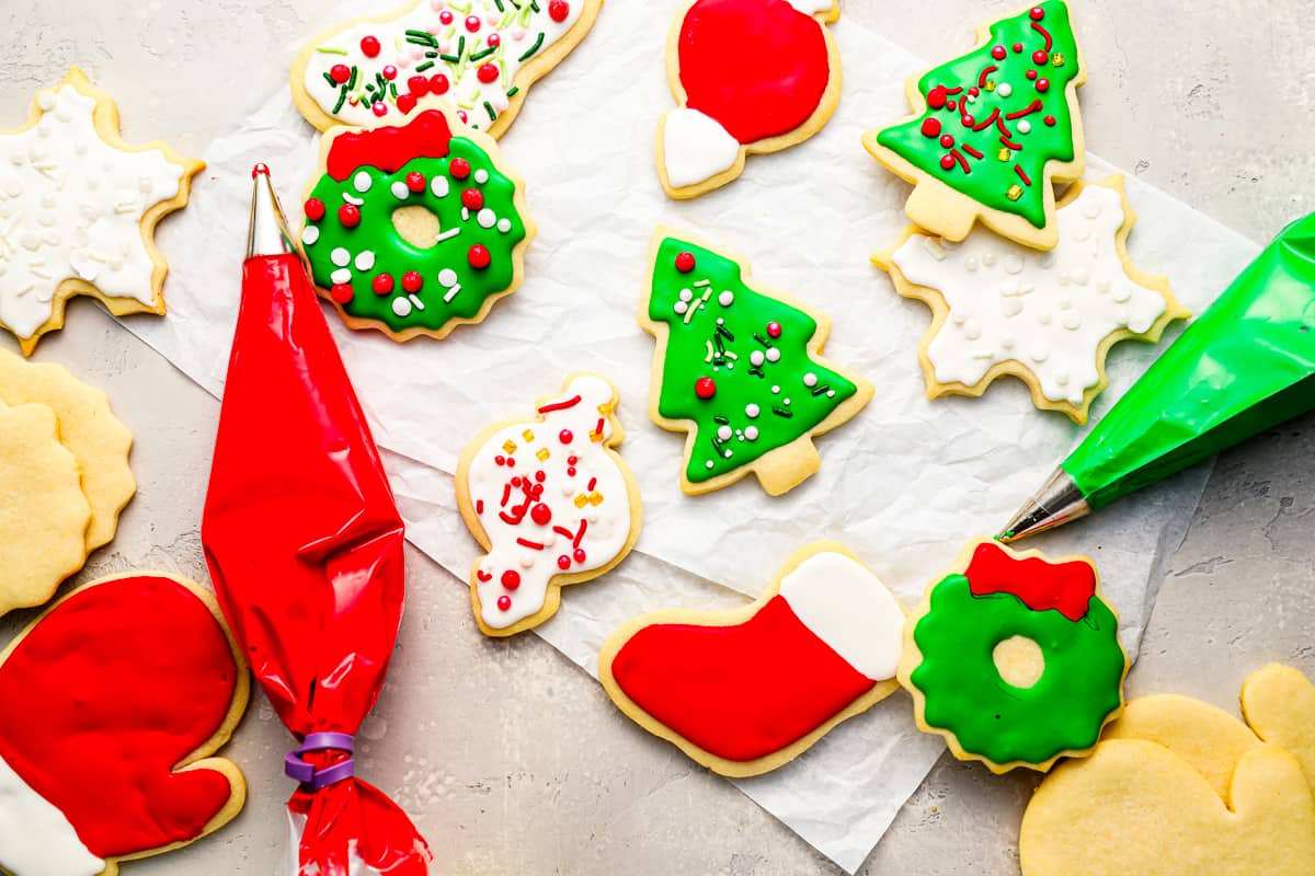 Christmas cookies are arranged on a table with bags of royal icing and decorations.