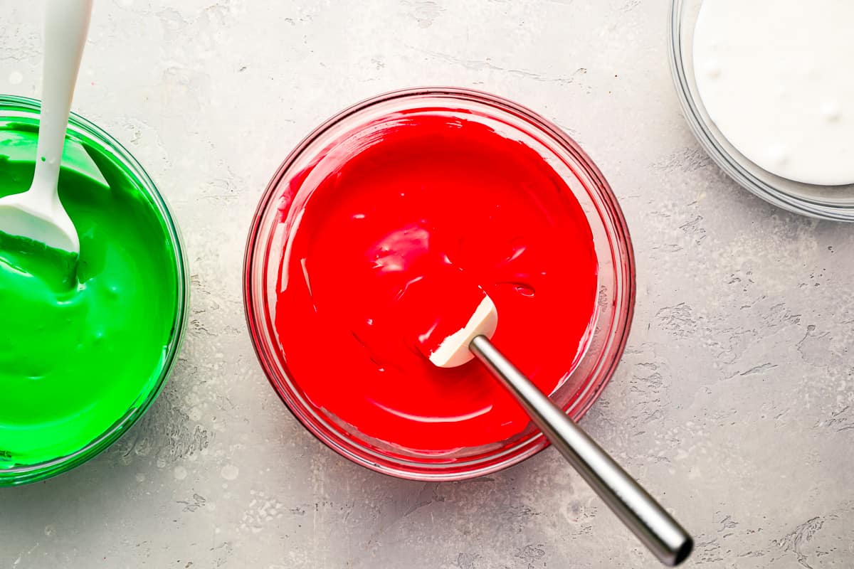 Three bowls of red, green, and white sugar cookie icing.