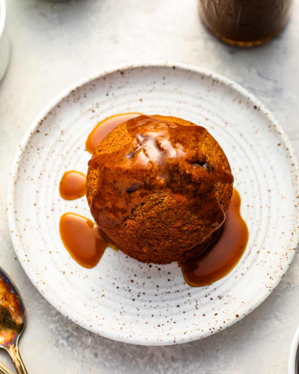 sticky date pudding on a white plate with toffee sauce.