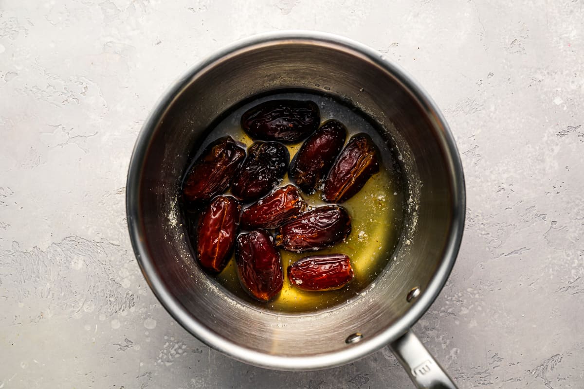 Dates in water in a pan on a table.