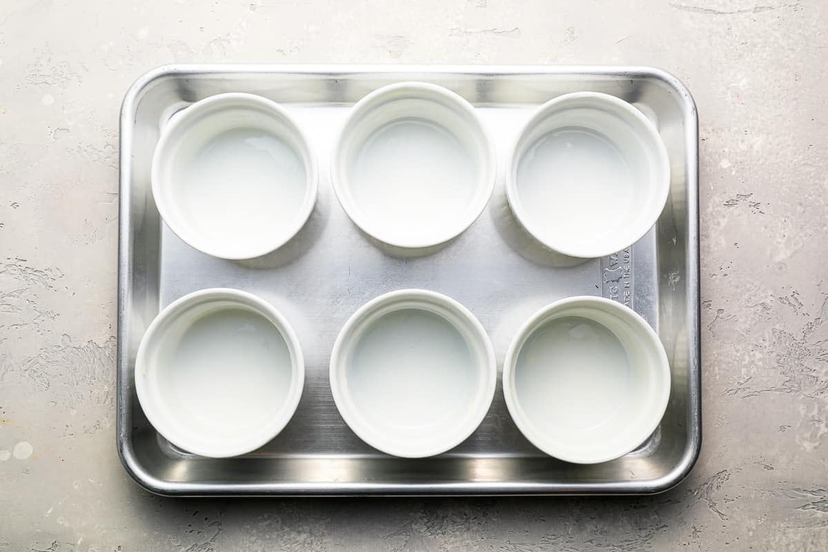 A tray with six white ramekins on it.