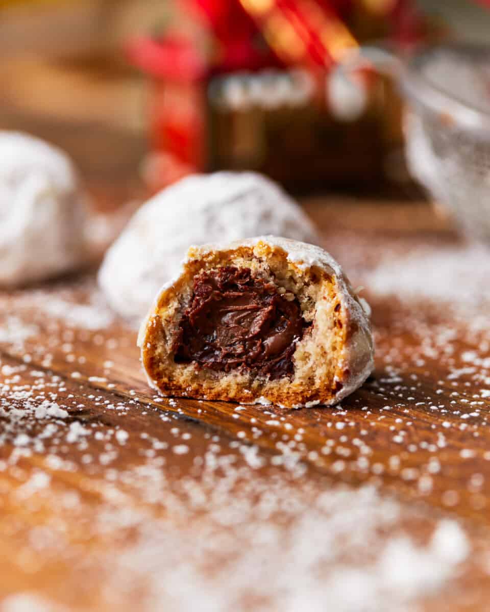 A nutella stuffed snowball cookie with a bite taken out of it.