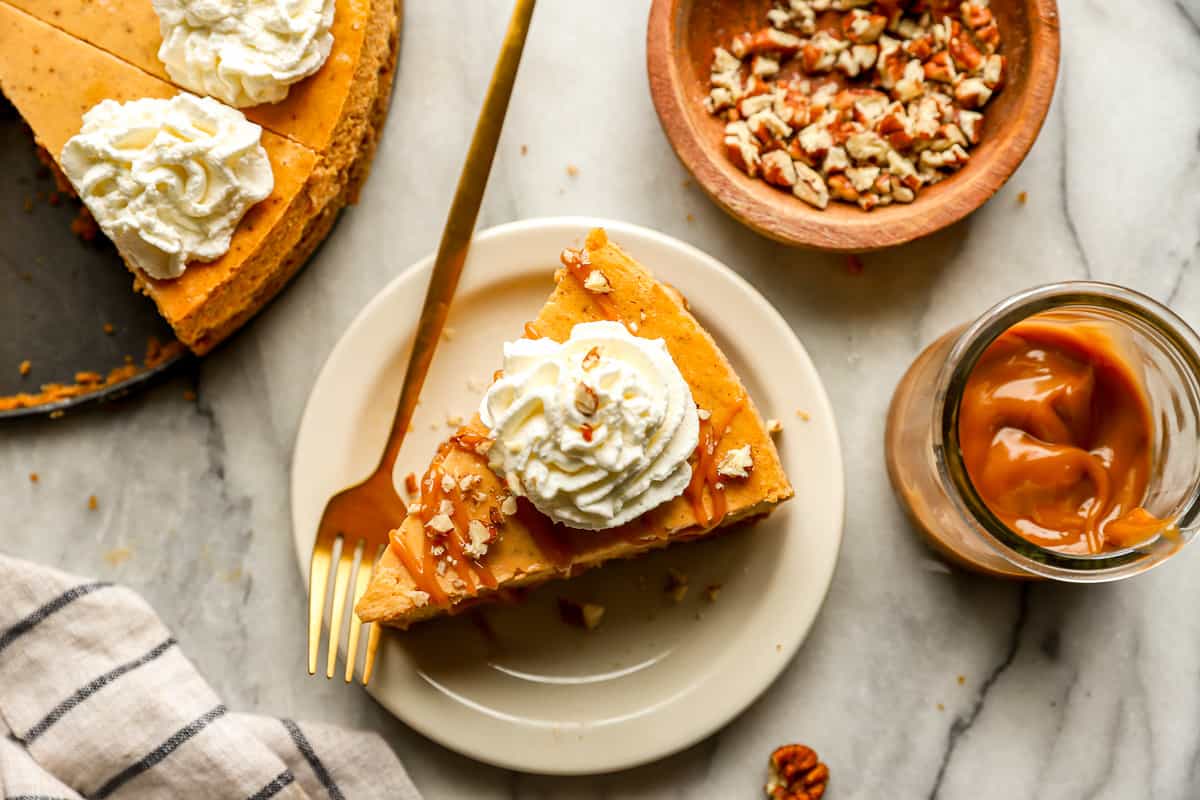 A slice of sweet potato cheesecake with whipped cream and pecans.