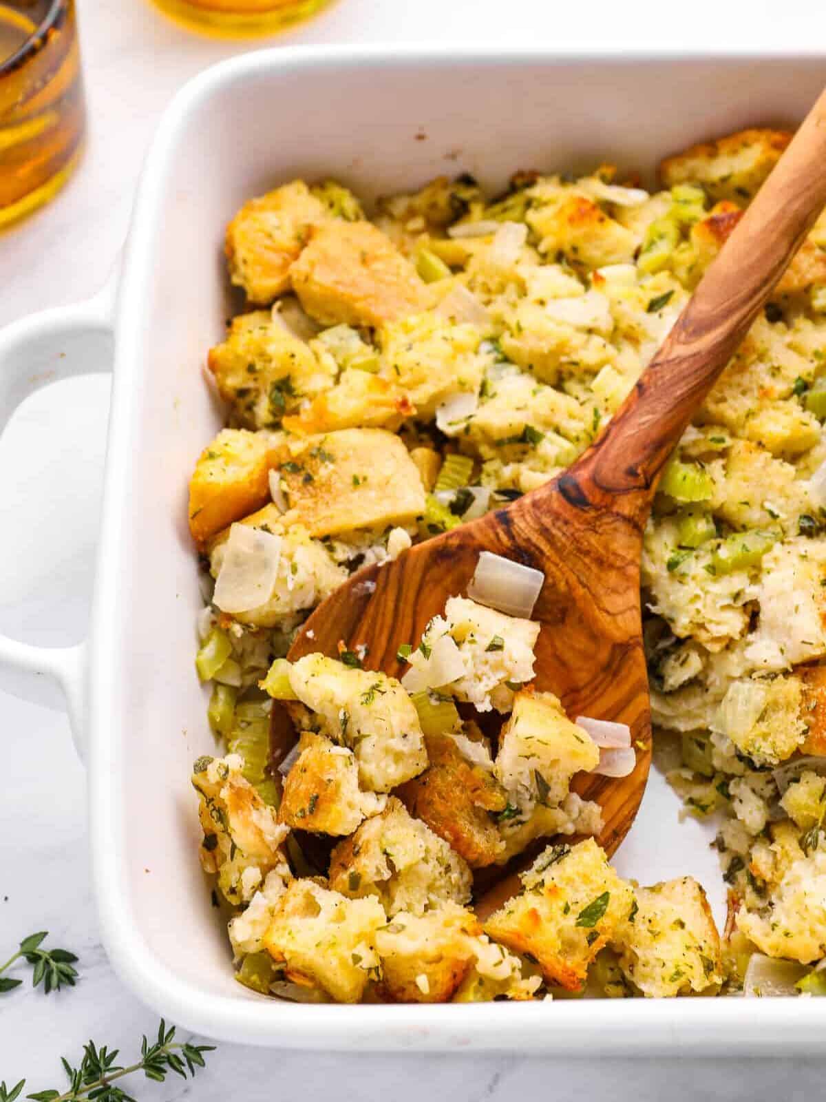 a spoon scooping vegetarian stuffing from a white baking dish.