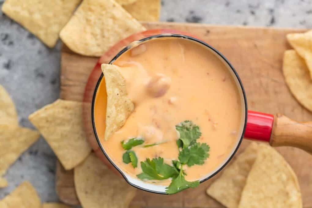 Overhead view of beer cheese dip in a fondue pot with tortilla chips.