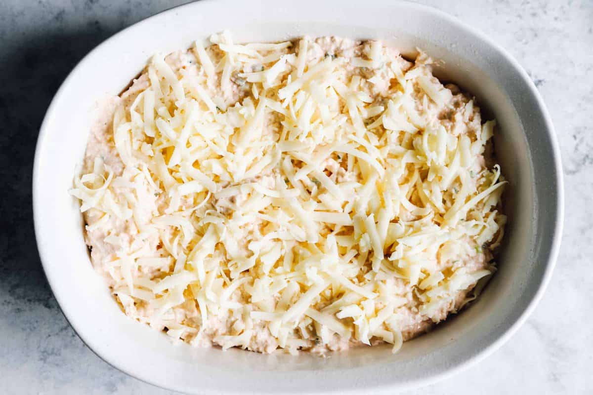 dip topped with cheese in a white oval baking dish.