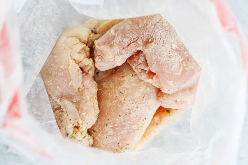 raw chicken breasts and seasoning in a ziplock bag.
