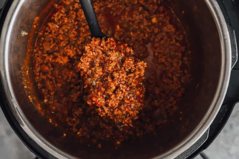 a spoon lifting a scoop of instant pot sloppy joes from an instant pot.