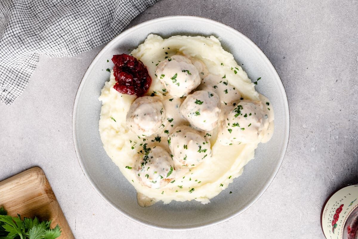 overhead image of crockpot swedish meatballs on top of mashed potatoes in a bowl