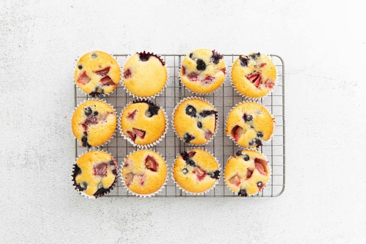 12 baked wildberry muffins on a wire rack.