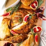 roasted turkey with pomegranate sauce on a cutting board.