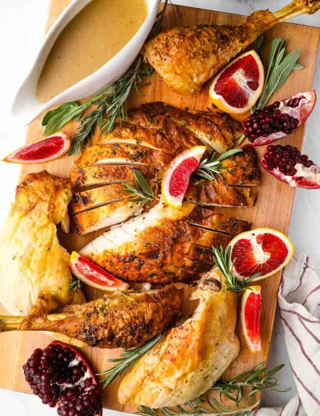 roasted turkey with pomegranate sauce on a cutting board.