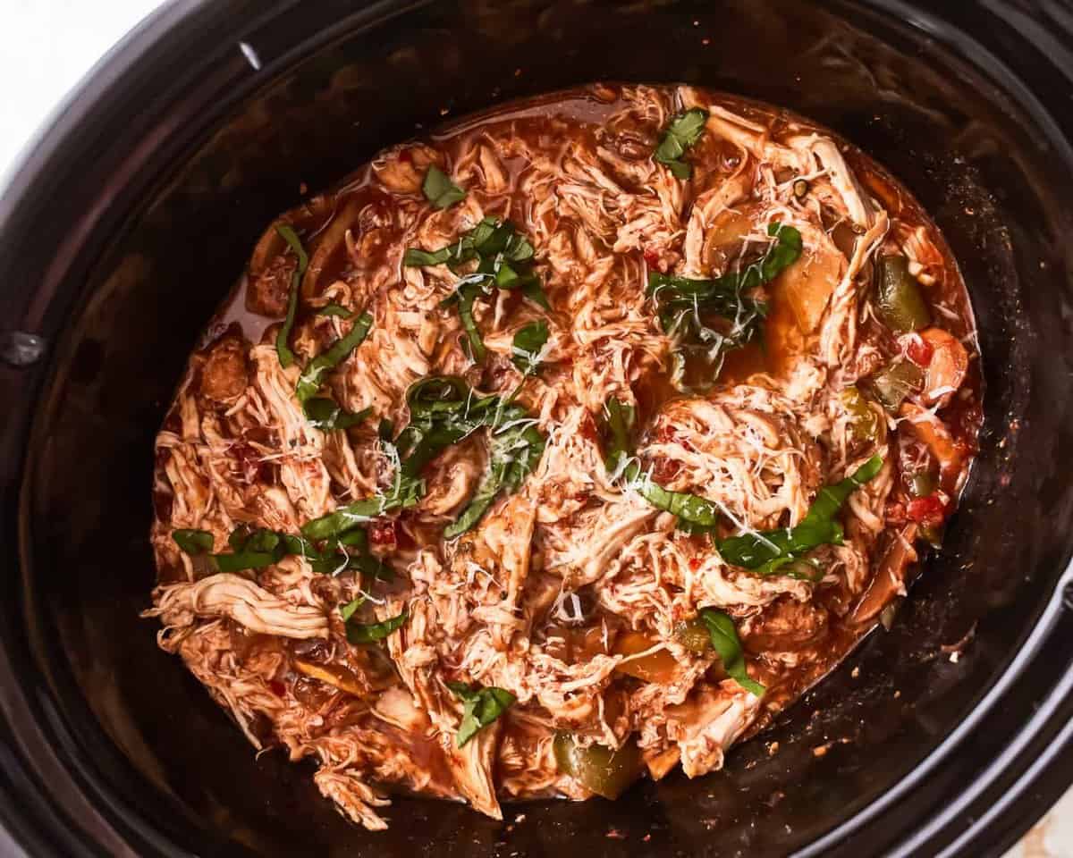 A crock pot full of chicken in a slow cooker.