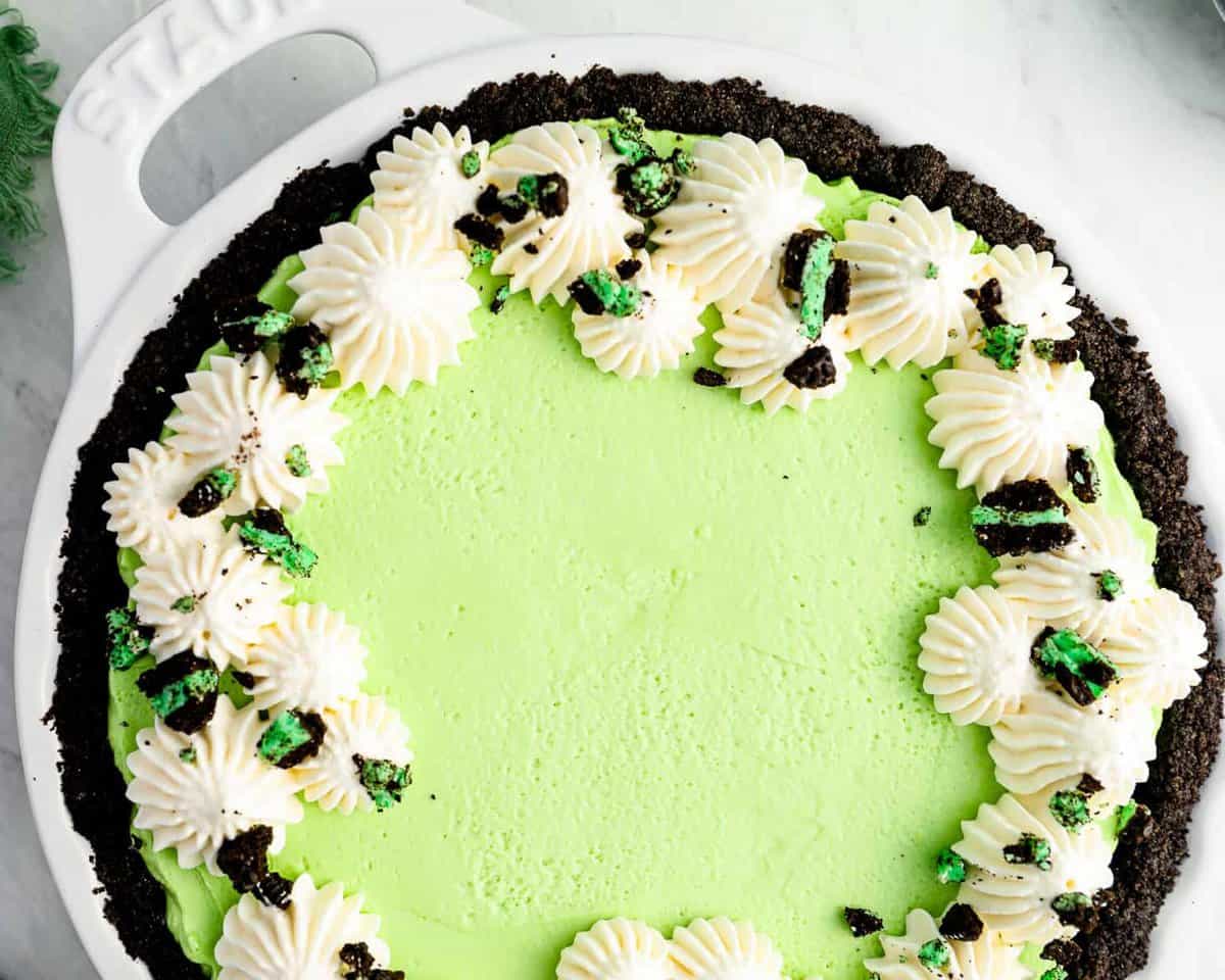 green mint chocolate pie in a white pie pan.