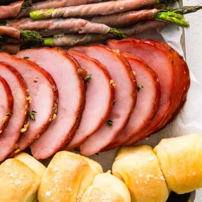 ham, prosciutto wrapped asparagus, and rolls on a sheet pan after baking