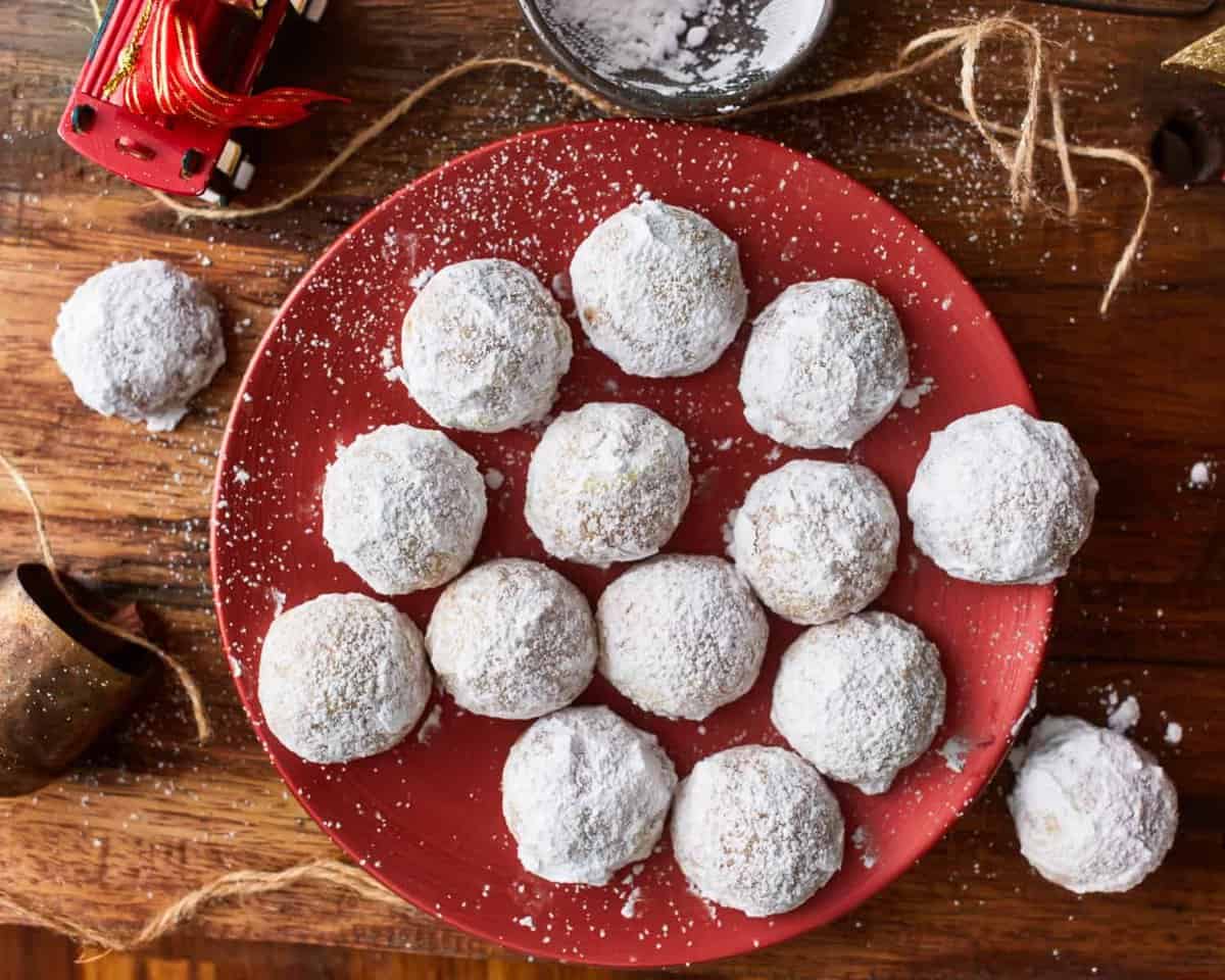 Powdered sugar cookies on a red plate.