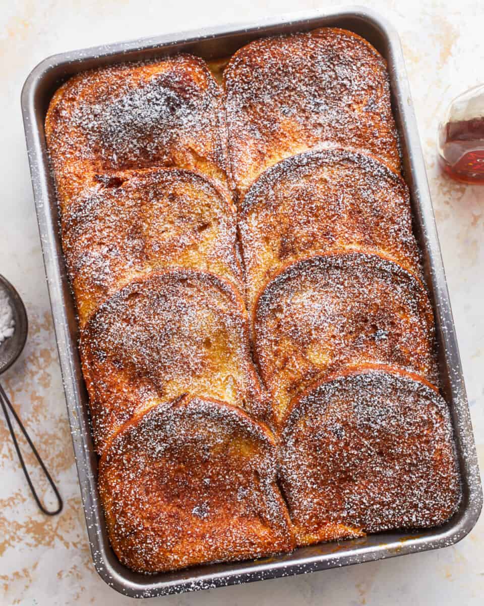 baked French toast in a casserole pan with powdered sugar.