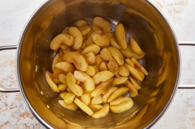 Sliced apples in a metal pot on a white background.