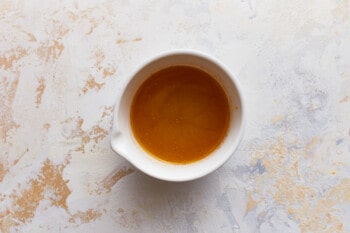 A bowl of sauce on a white surface.