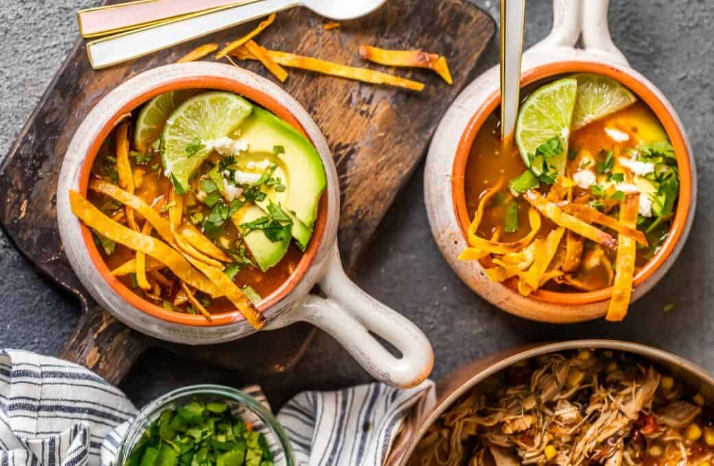 Bowl of chicken tortilla soup topped with corn strips and avocado