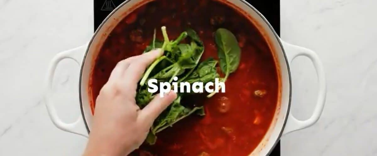Adding fresh spinach to the pot. 