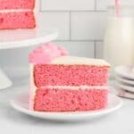 side view of a slice of pink velvet cake on a white plate.