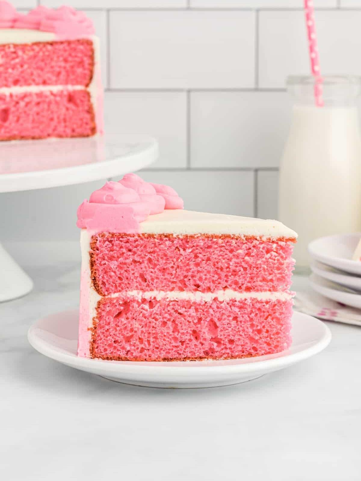 side view of a slice of pink velvet cake on a white plate.