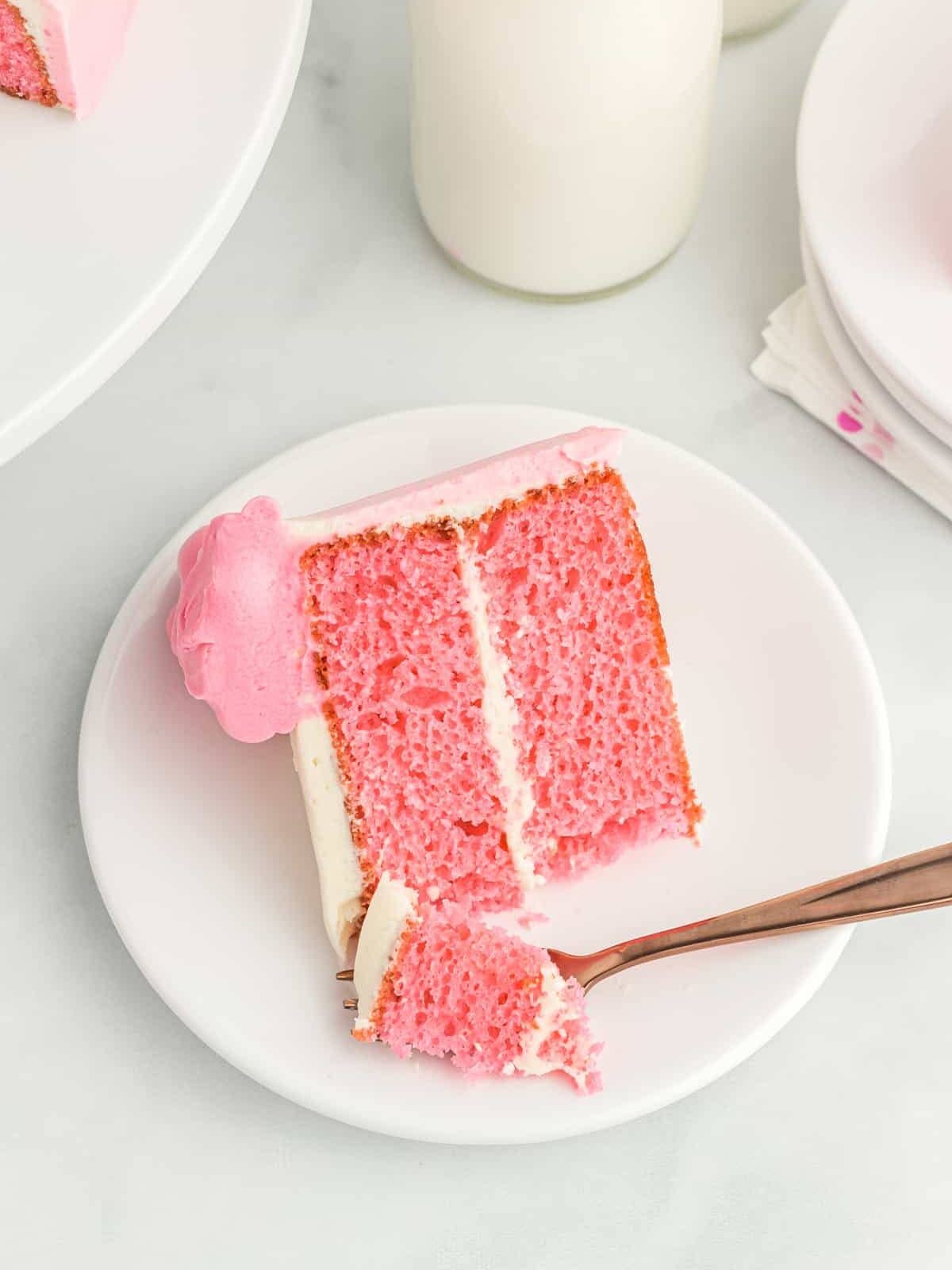 overhead view of a slice of pink velvet cake on its side on a white plate with a fork.