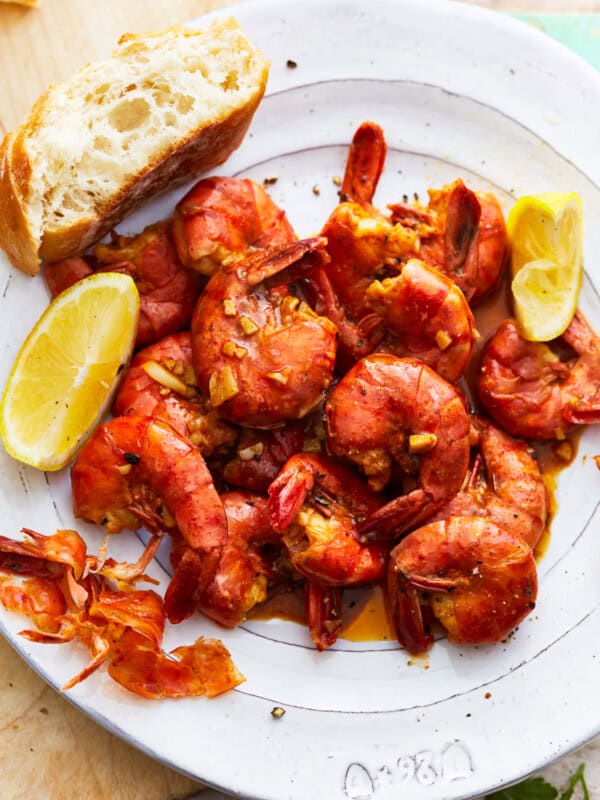 A plate with BBQ shrimp and bread on it.