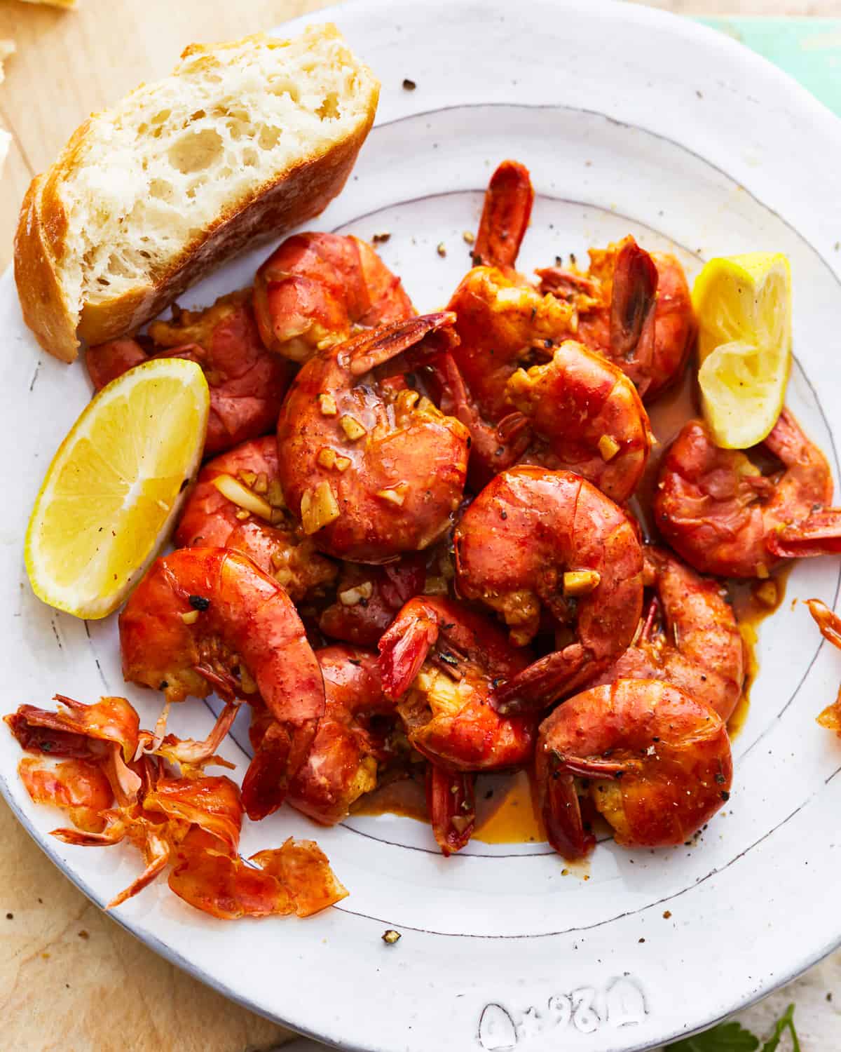 A plate with New Orleans BBQ shrimp and bread on it.