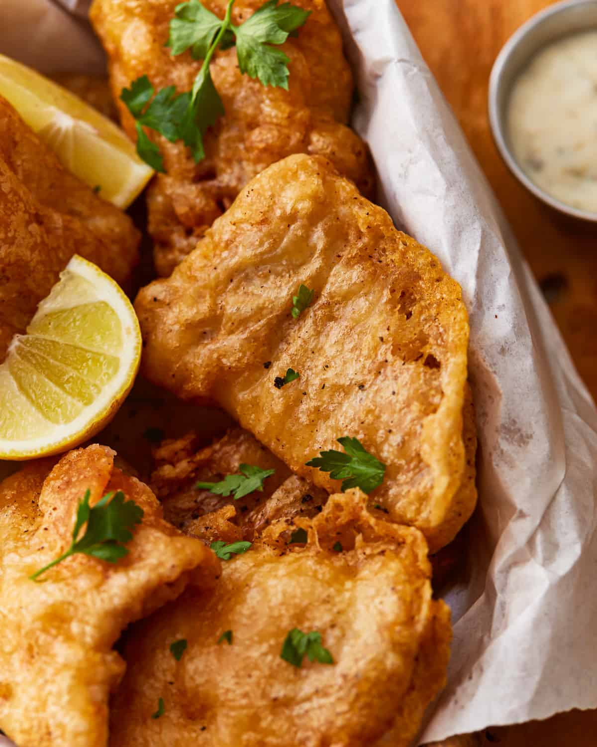 Beer-battered fried fish with lemon wedges and dipping sauce.