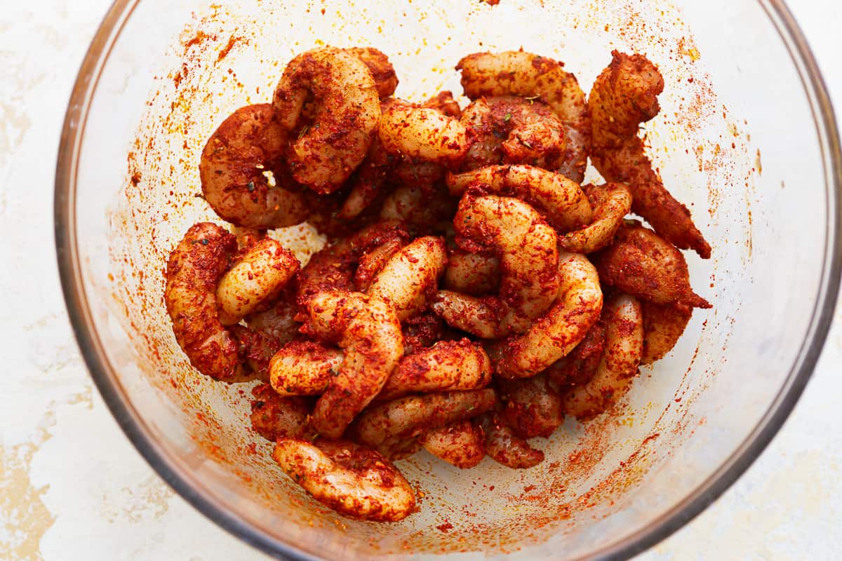 Seasoned raw shrimp in a glass bowl.