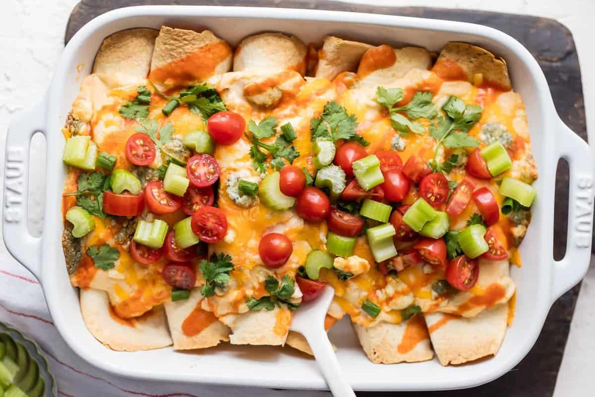 Buffalo Chicken Enchiladas topped with tomatoes, celery, cilantro