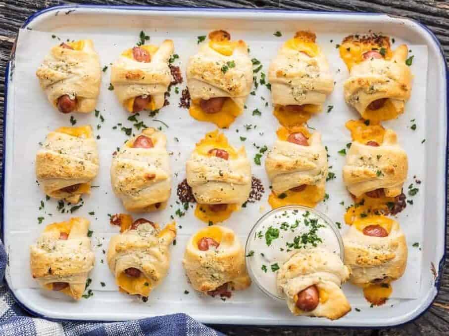 overhead shot of pigs in a blanket with cheese dipped in ranch dipping sauce