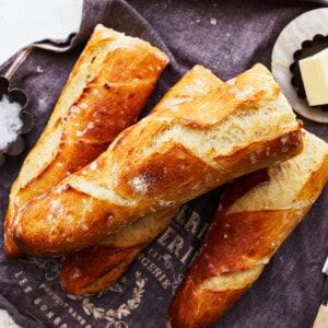 A bunch of french baguette on a napkin with butter and a knife.