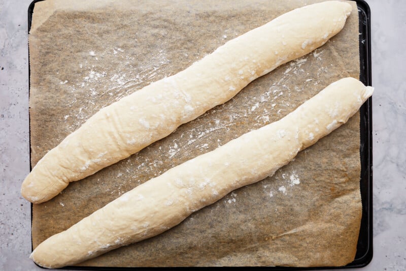 Two pieces of French baguette on a baking sheet.