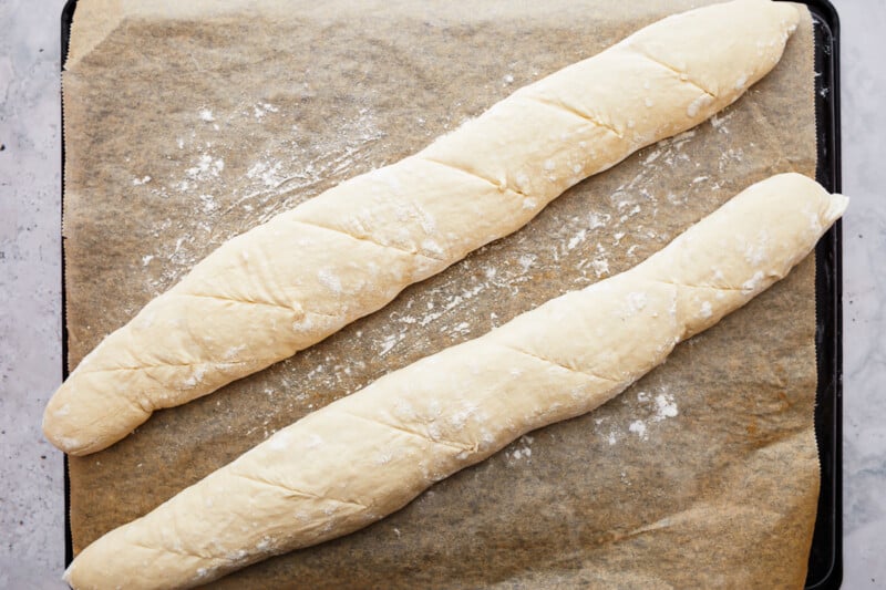 Two pieces of a French baguette on a baking sheet.