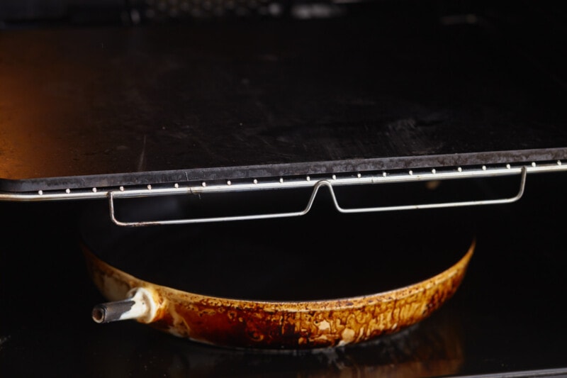 A black oven with a french baguette in it.