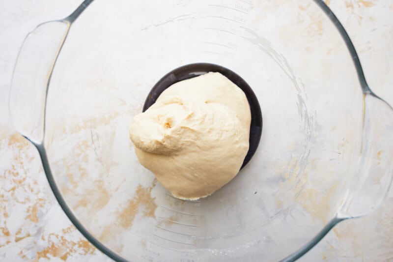 A dough ball in a glass bowl, ready to be shaped into a French baguette.