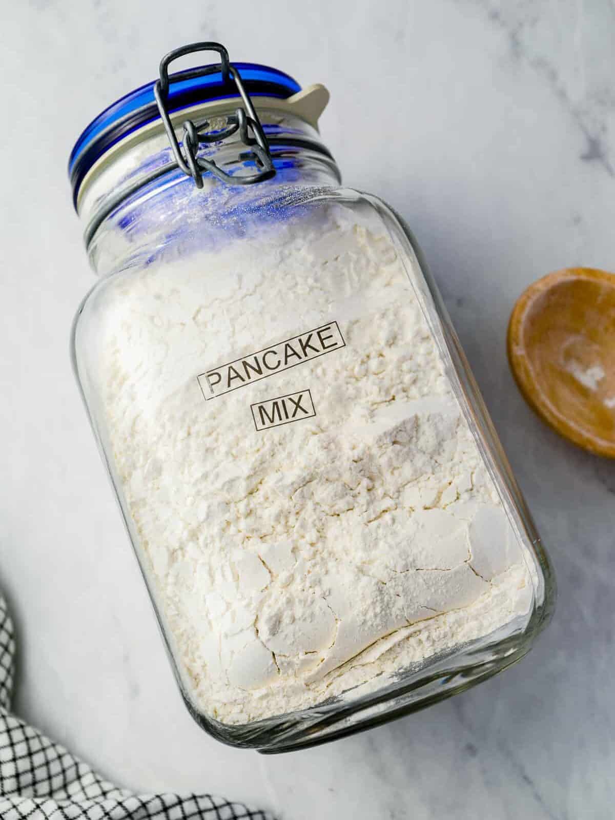 overhead view of a glass jar full of homemade pancake mix on its side with the label "pancake mix".