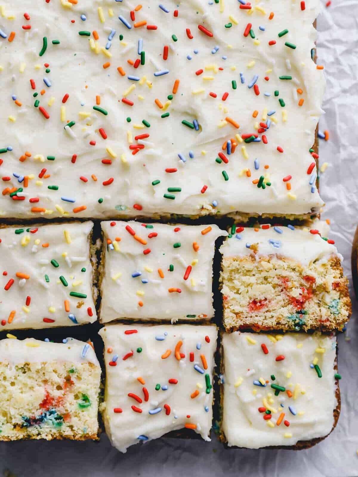 close up view of partially cut funfetti birthday cake topped with sprinkles