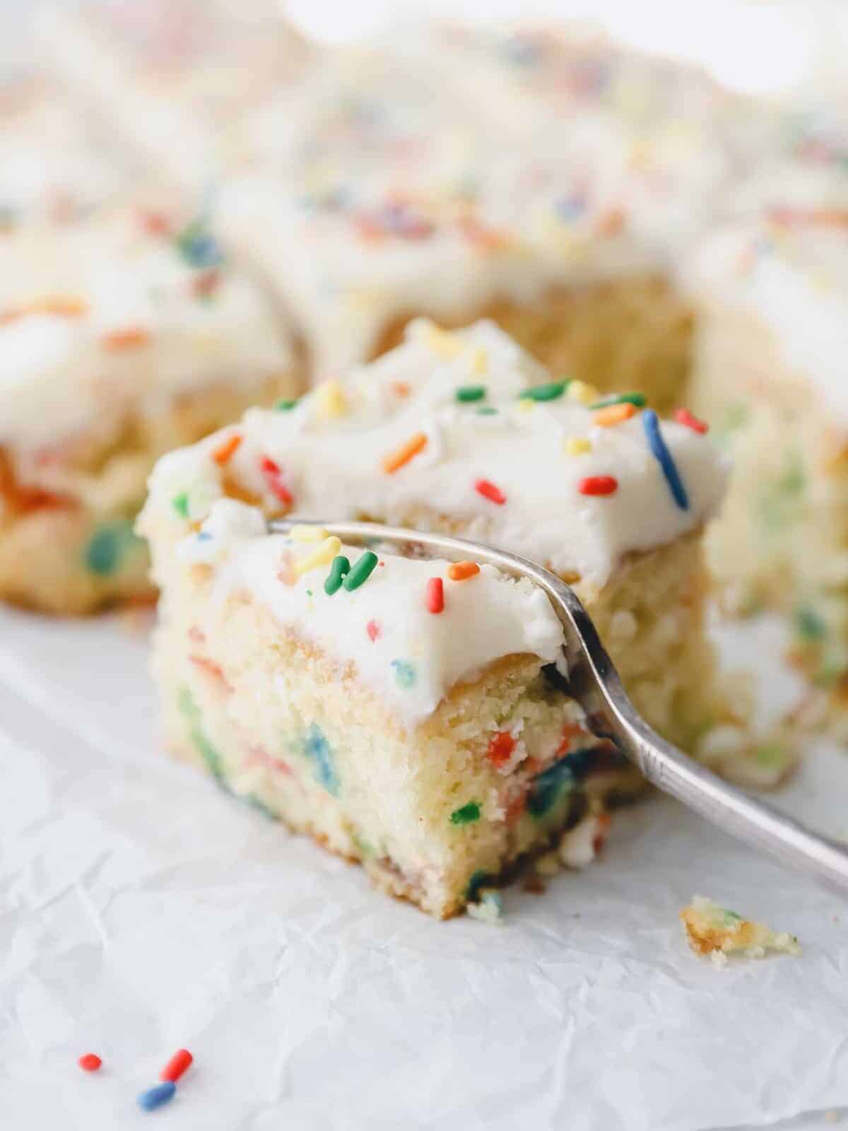 close up of a slice of sheet pan funfetti cake being cut through with a fork.