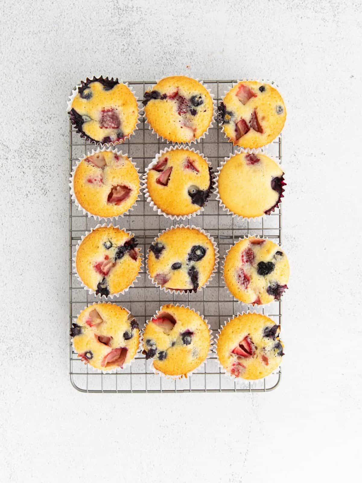 12 baked wildberry muffins on a wire rack.